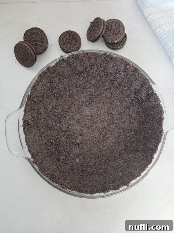 Easy Oreo Pie Crust 8 Oreo Crust in a pie dish with a couple of Oreo Cookies and a blue napkin