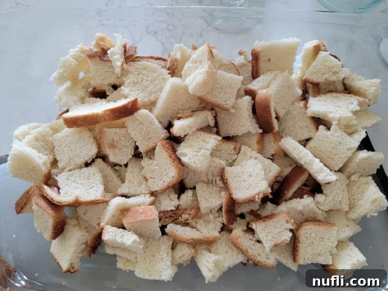 Cubed bread pieces neatly arranged in a greased casserole dish, forming the base for the Overnight French Toast Casserole.