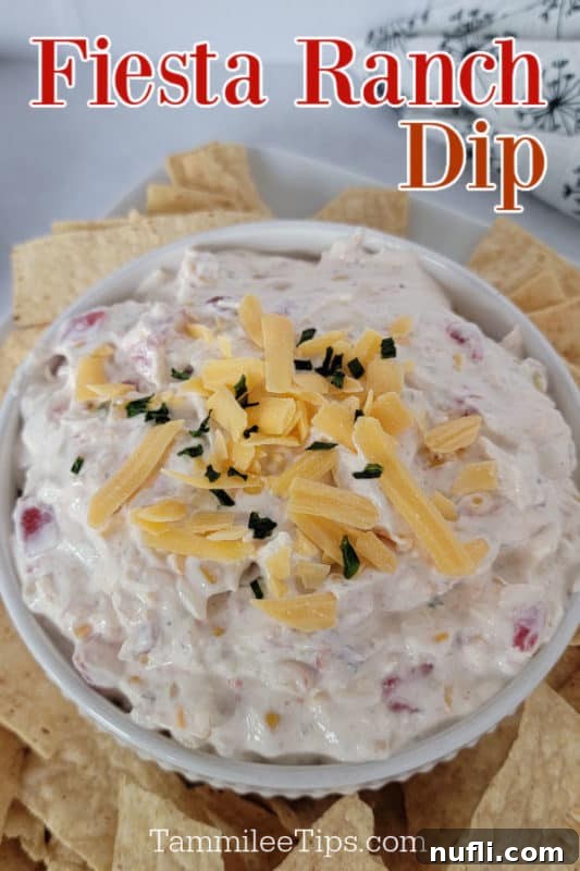 A bowl of creamy Fiesta Ranch dip surrounded by crispy tortilla chips on a pristine white platter, inviting guests to dig in.