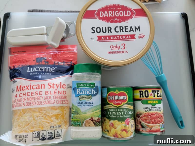 Essential Fiesta Ranch dip ingredients: a can opener, a tub of sour cream, a bag of Mexican-style four cheese blend, a packet of Ranch seasoning, a can of Southwest corn, and Rotel diced tomatoes, all neatly arranged on a plastic cutting board.