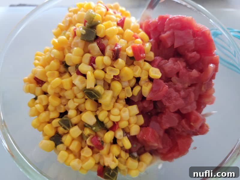 Drained Southwest corn and Rotel diced tomatoes with green chilies in a clear glass bowl, ready to be mixed into the dip.