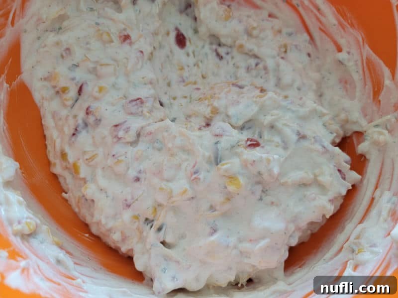 A vibrant, creamy Fiesta Ranch dip mixture in an inviting orange mixing bowl, showcasing its ready-to-serve texture.