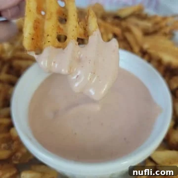 Waffle fry dipping into a bowl of homemade fry sauce