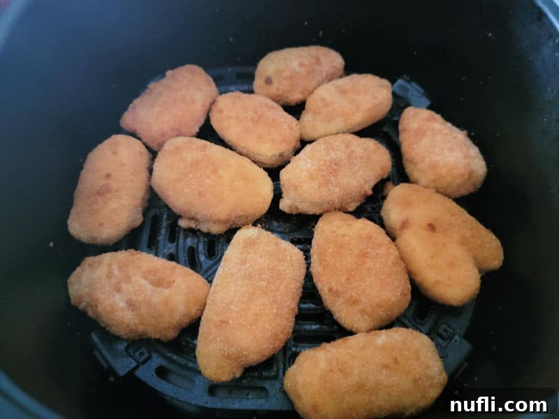 Crispy Air Fryer Frozen Jalapeno Poppers 4 Frozen jalapeno poppers arranged in a single layer in an air fryer basket.