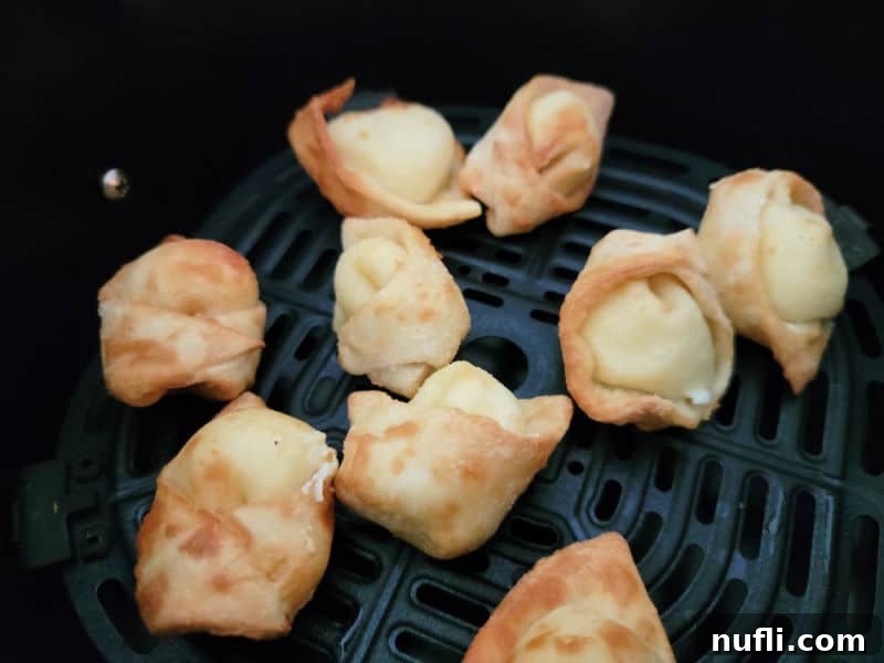 Freshly air-fried, golden-brown cream cheese wontons glistening in the air fryer basket, ready to be served