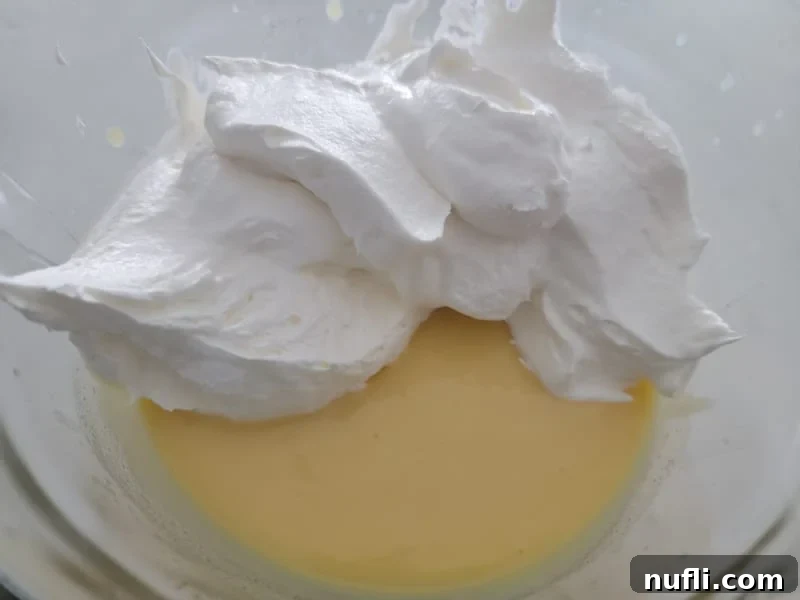 Cool Whip whipped topping being gently folded into the vanilla pudding and RumChata mixture.