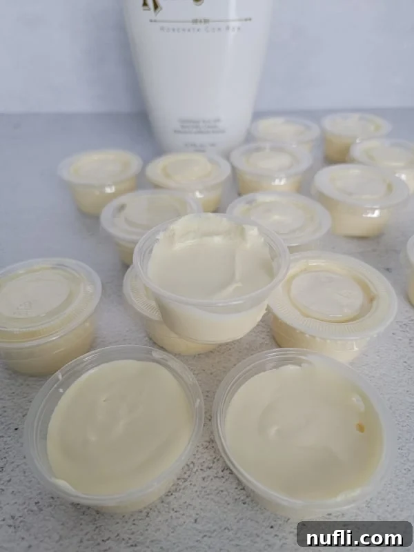 Ready-to-serve RumChata Pudding Shots in plastic Jello Shot cups, positioned in front of a RumChata bottle