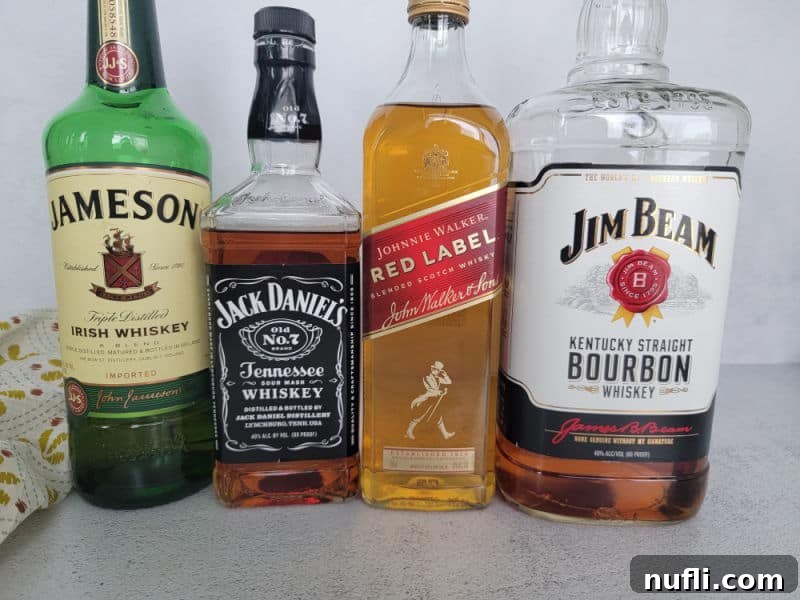 Jameson Irish Whiskey, Jack Daniels Tennessee Whiskey, Johnnie Walker Red Label, and Jim Beam Kentucky Bourbon bottles on a white counter.