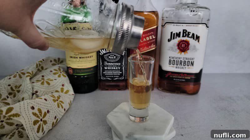 Mason jar cocktail shaker pouring into a shot glass