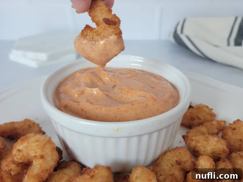 Effortless Homemade Yum Yum Sauce 6 Air fryer shrimp dipping into a white bowl filled with homemade Yum Yum Sauce