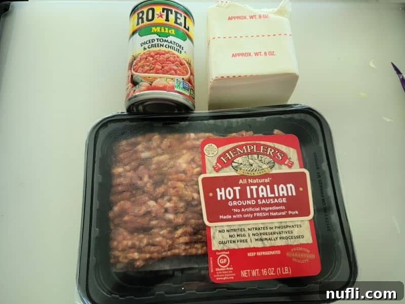 Can of Rotel diced tomatoes and green chilies, cream cheese, and hot Italian ground sausage on cutting board.
