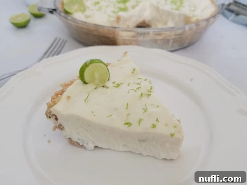 Cool & Creamy Key Lime Pie 7 Slice of no bake key lime pie on a white plate next to a fork with the pie in the background