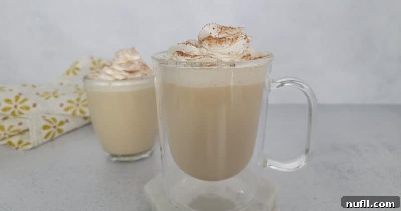 Eggnog coffee with a whipped cream garnish and cinnamon in a glass mug