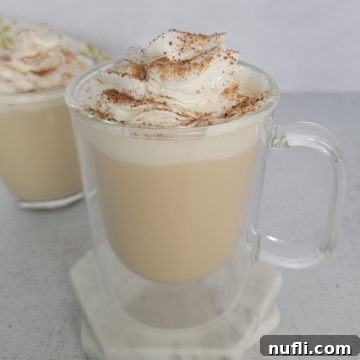 Eggnog coffee with a whipped cream garnish and cinnamon in a glass mug