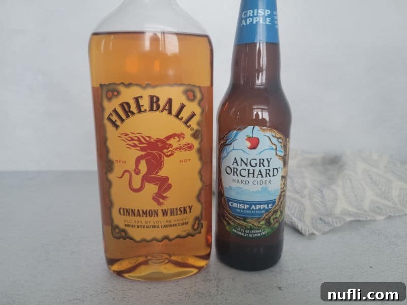 Bottle of Fireball cinnamon whiskey next to a bottle of Angry Orchard hard cider