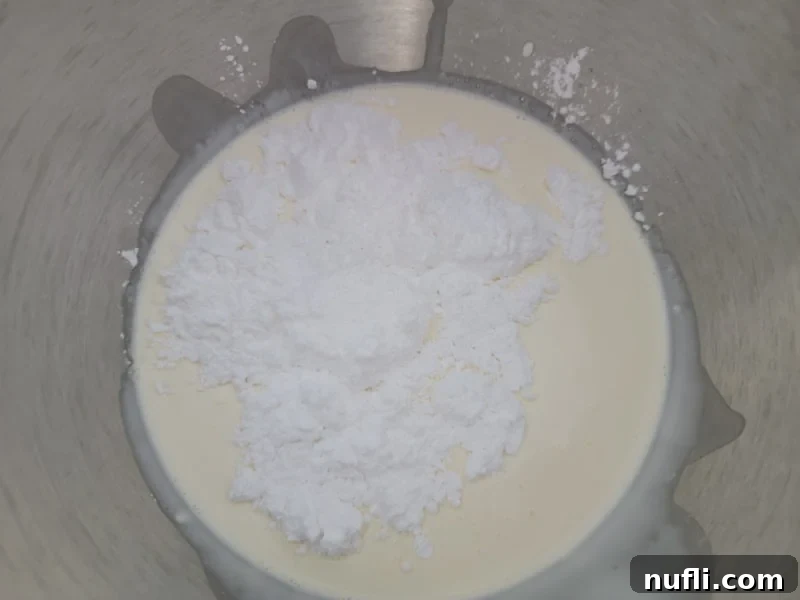 Heavy whipping cream and Confectioners sugar in a metal mixing bowl