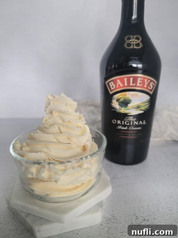 Glass bowl with Baileys whipped cream in it next to a bottle of Baileys Irish Cream. 