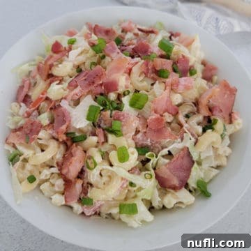 BLT pasta salad garnished with green onion in a white bowl