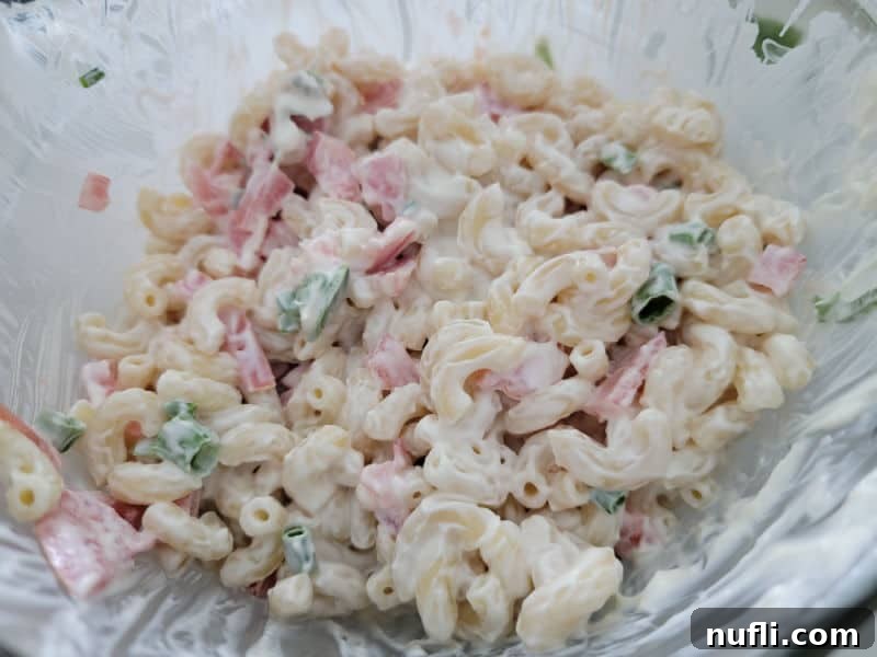 Mayo covered macaroni and tomatoes in a glass bowl 