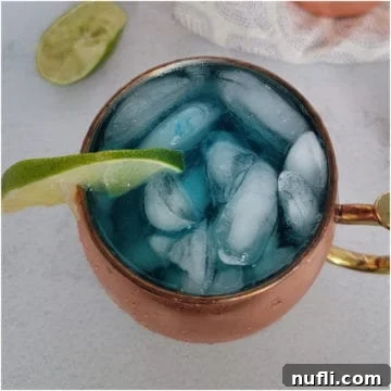 Blue mule in a copper mug with a lime wedge and limes nearby