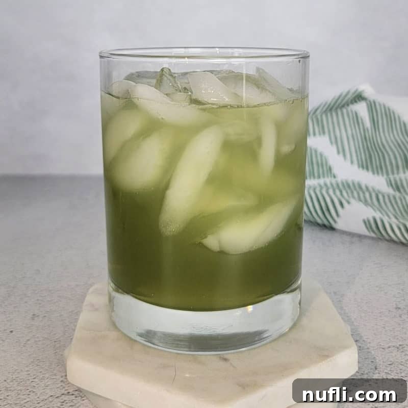 St Patrick's Day Sips & Shots 6 The Incredible Hulk Drink, a vibrant green cocktail, perfectly presented in a clear cocktail glass, resting on a crisp white coaster, ready to energize any party.