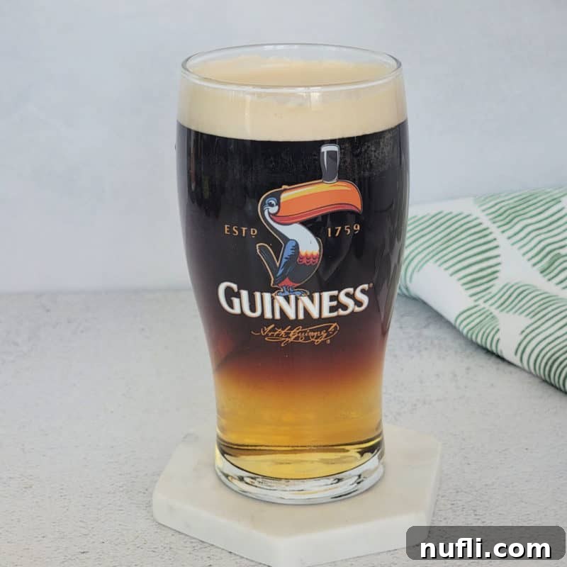 St Patrick's Day Sips & Shots 8 A striking layered cocktail of Guinness and Cider, presented on a pristine white coaster, showcasing the dark stout beautifully balanced with the lighter cider for a unique beer cocktail.