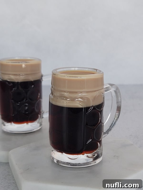 Two perfectly layered Baby Guinness Cocktails in mini beer glasses, ready to be enjoyed.