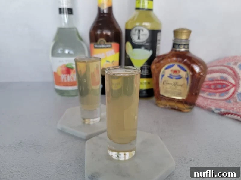 Two Water Moccasin shots on white coasters in front of bottle of liquor