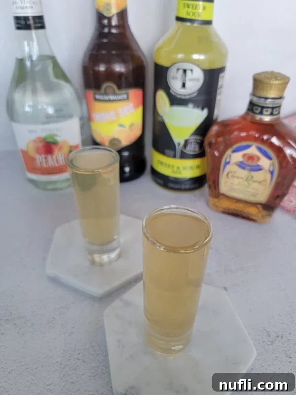 Two water moccasin shots on white coasters in front of liquor bottles