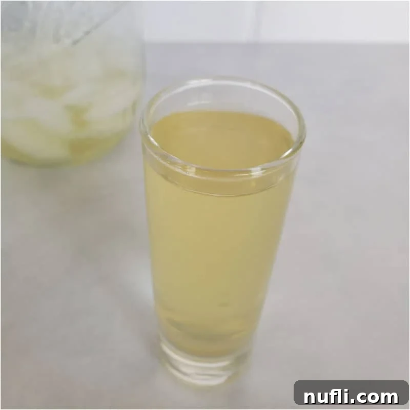 Green tea shot in a clear shot glass next to a mason jar