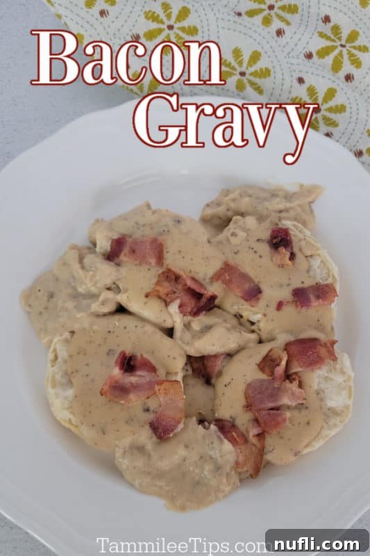Bacon gravy over biscuits on a white plate with a cloth napkin in the background