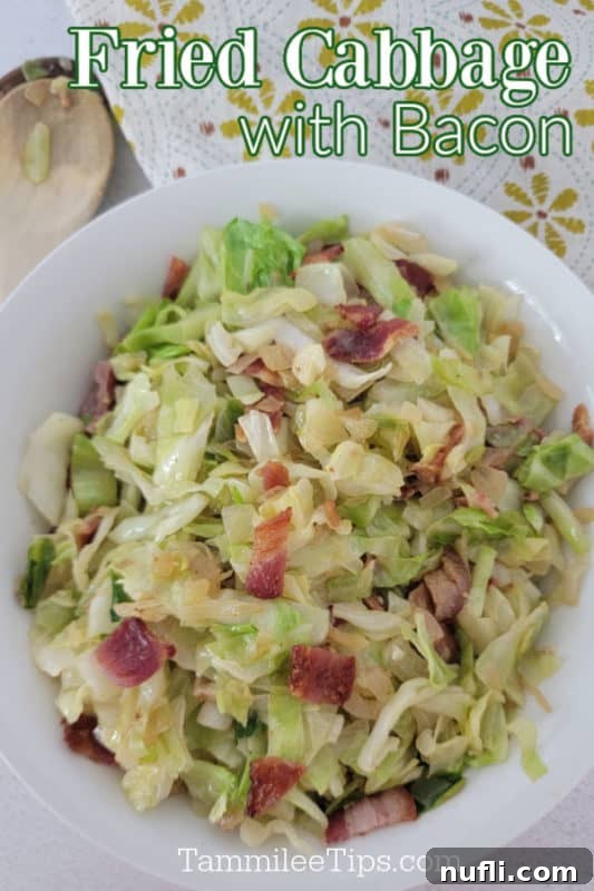 Fried Cabbage with bacon over a white bowl with cabbage and bacon next to a wooden spoon and cloth napkin