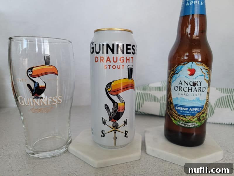 Guinness glass with toucan on it, Guinness can with toucan on it, and a bottle of Angry Orchard Hard Cider