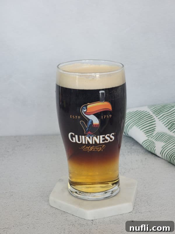 Guinness glass with layered drink next to a cloth napkin 