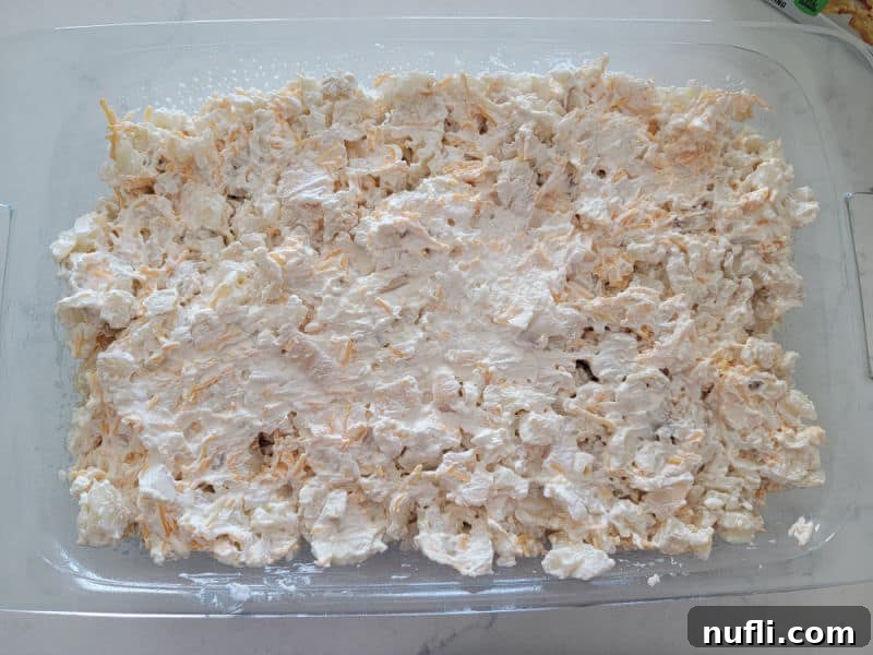 Diced potatoes with cheese in a glass baking dish before baking