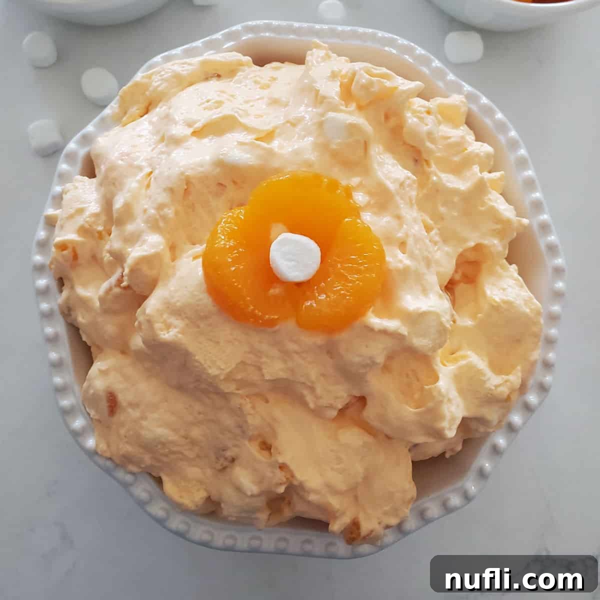 Orange Dreamsicle Salad in a white bowl with orange and mini marshmallow garnish