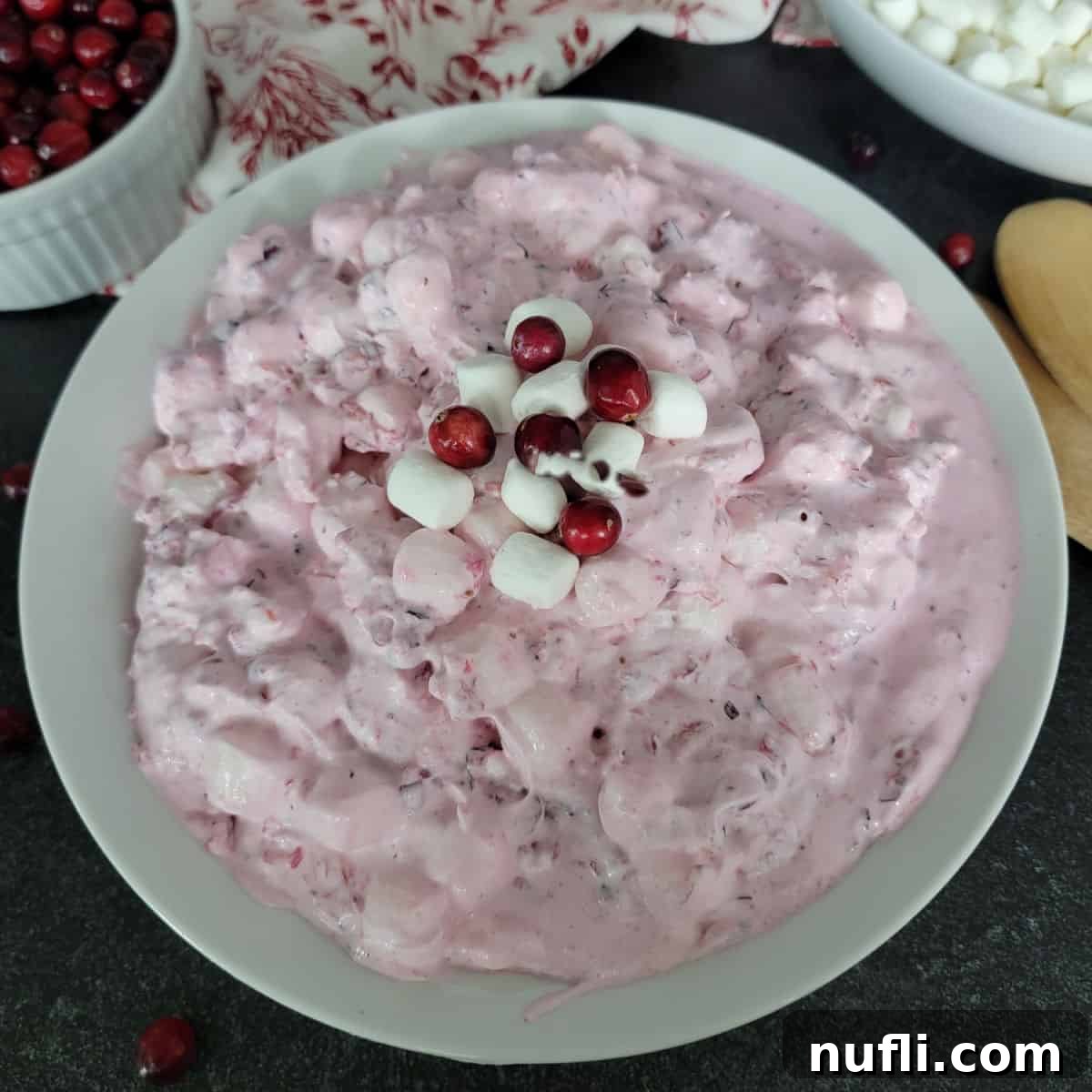Cranberry Fluff Salad in a white bowl next to cranberries