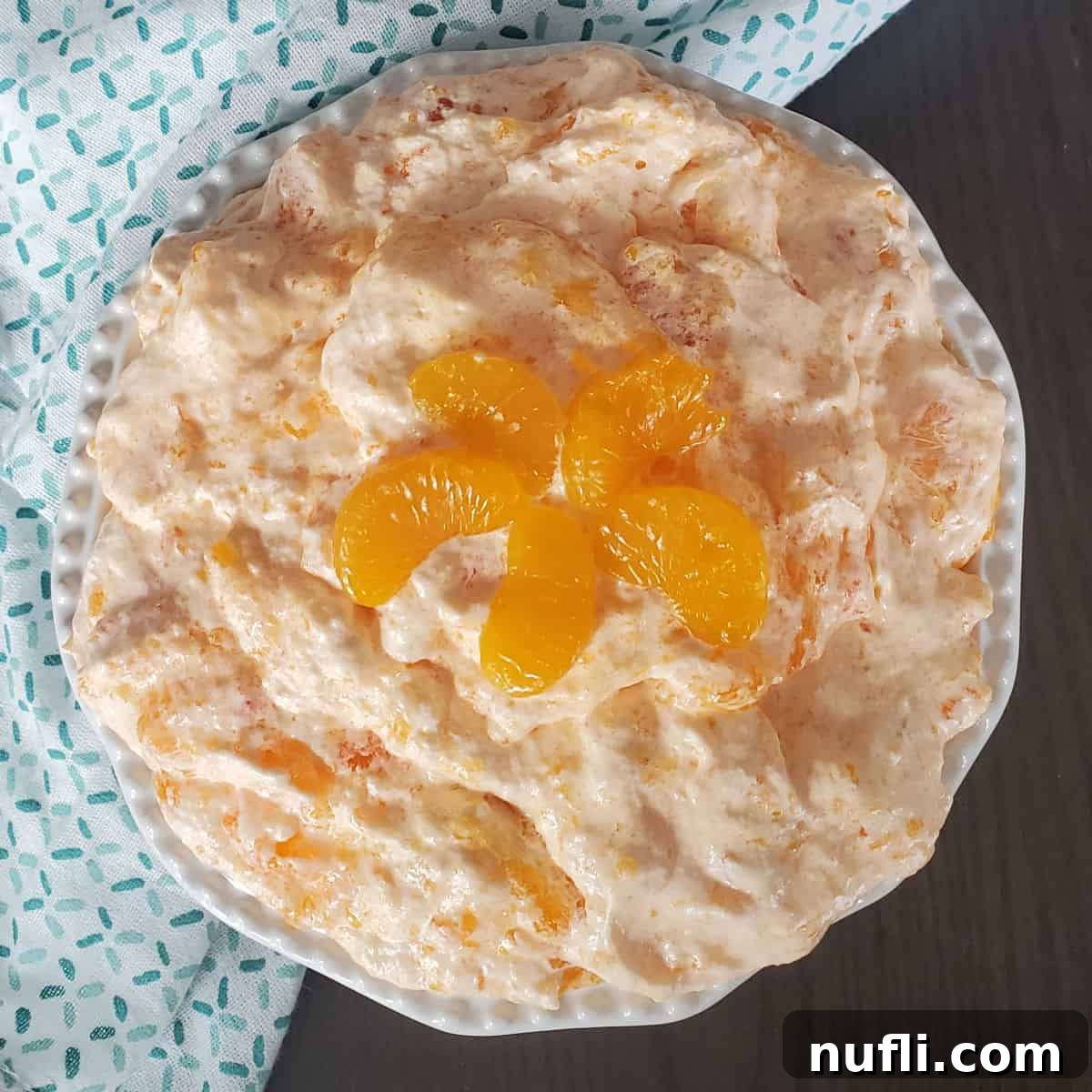 Mandarin Orange Jello Salad in a white bowl with orange slice garnish