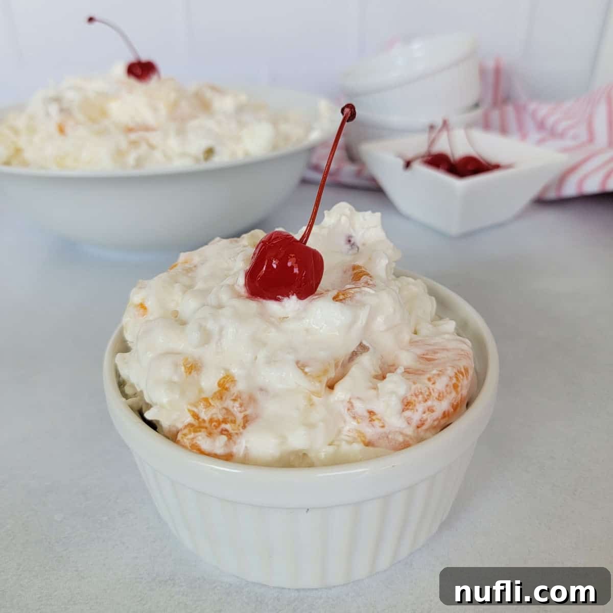 ambrosia salad with a maraschino cherry in a small ramekin.