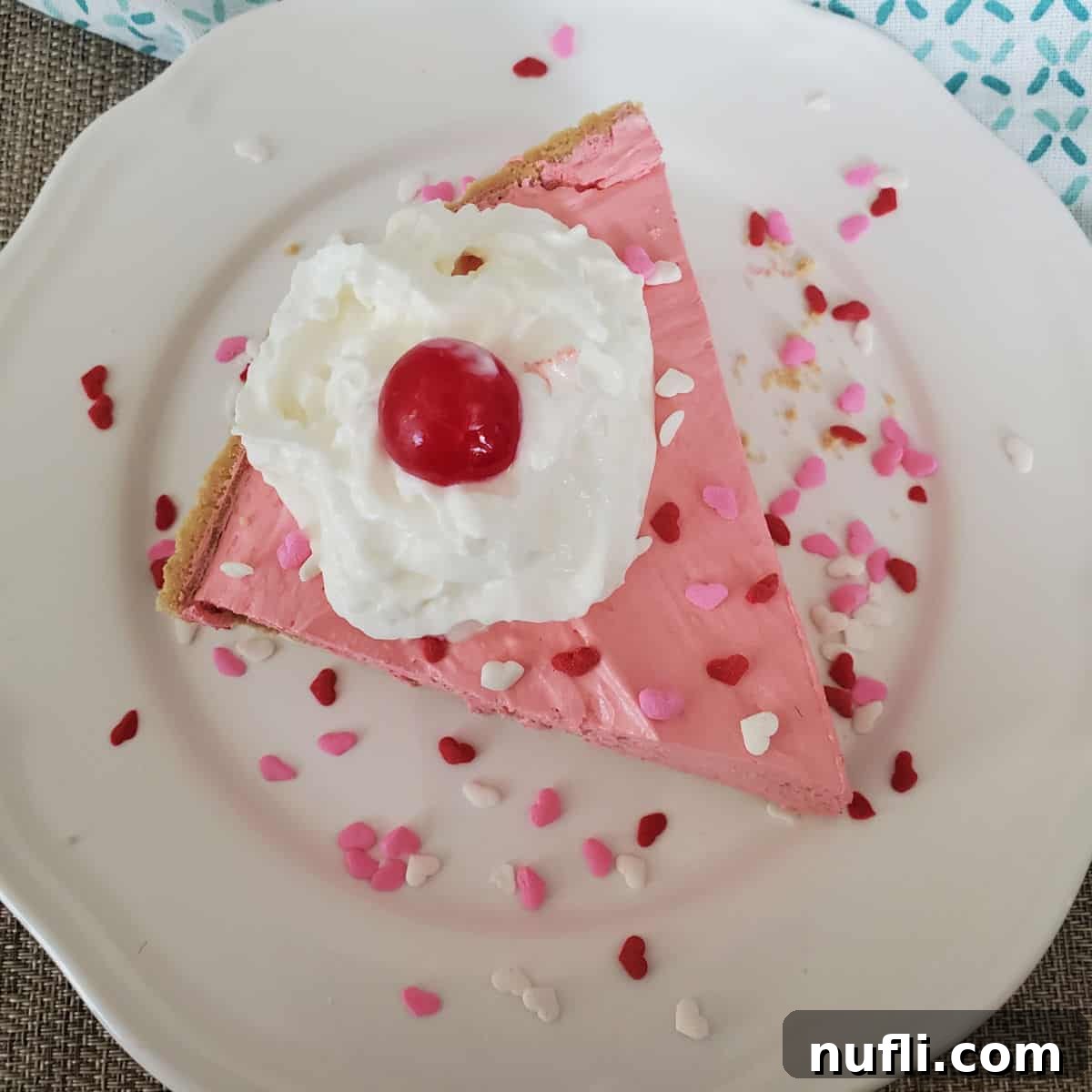 Slice of pink Kool Aid Pie on a white plate with heart sprinkles