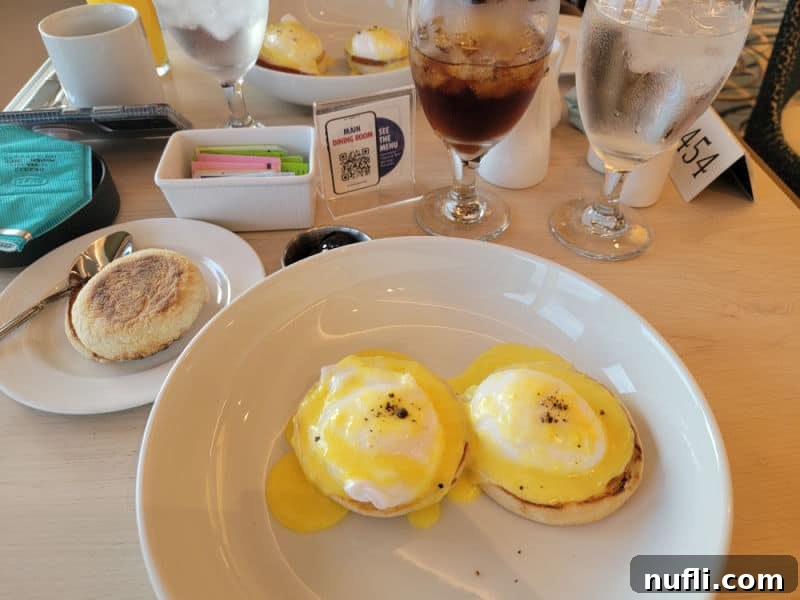 Carnival Radiance 4-Day Baja Mexico Escape 22 Eggs benedict on a white plate next to a English Muffin and glass of iced tea