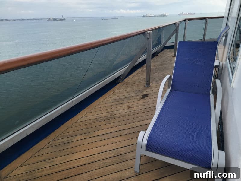Spacious wrap-around balcony on Carnival Radiance with a lounge chair, offering panoramic views of the ocean and ships