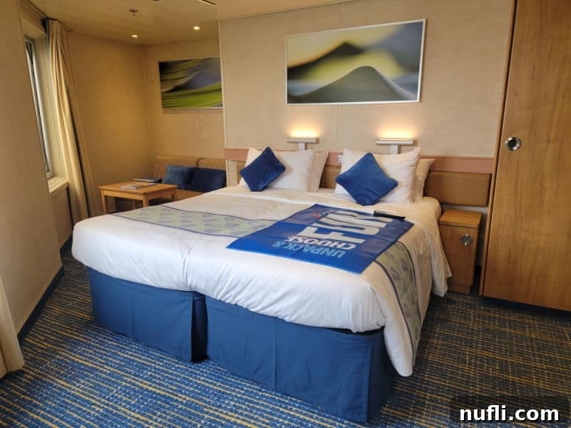 Comfortable cruise cabin bedroom with 'Choose Fun' mat, ambient lighting, and elegant blue carpet, ready for relaxation