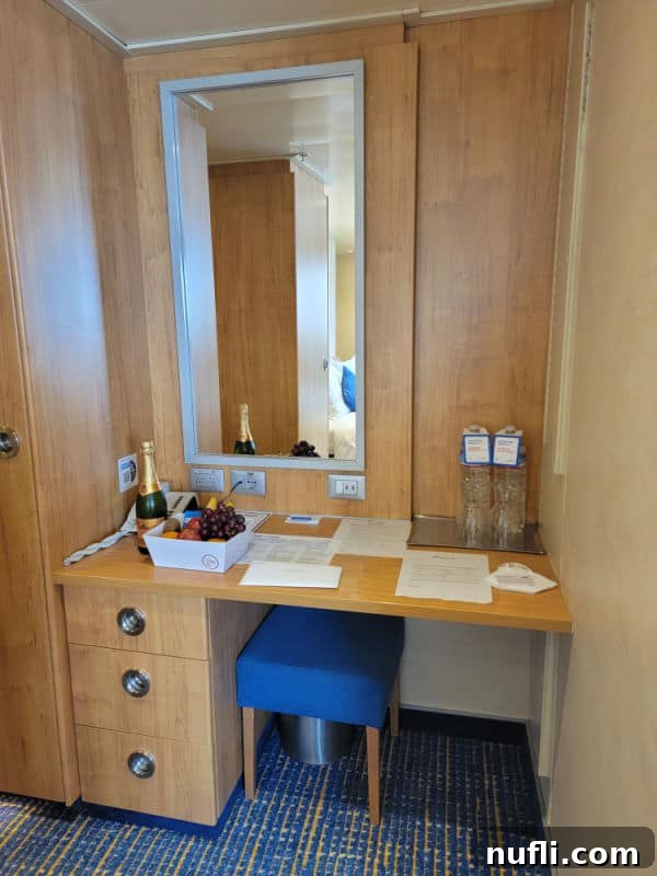 Functional built-in desk with a large mirror, adorned with a bottle of champagne and a fruit basket, ready for use
