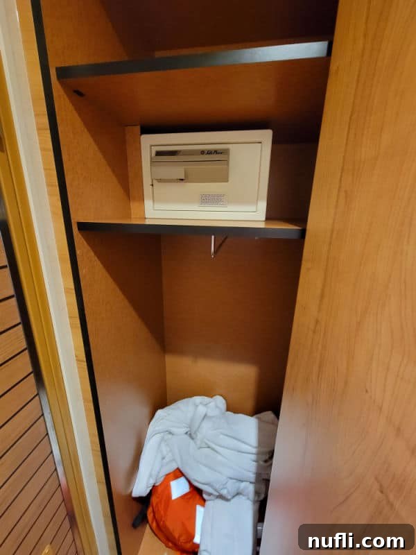 Secure safe located inside a cruise cabin closet, alongside robes and neatly stored life jackets, for guest convenience