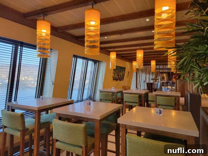 Lights hanging over tables with tall chairs view of the ocean out the windows