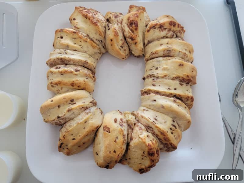 Delicious Easy Cinnamon Roll King Cake 6 Baked cinnamon rolls in a circle on a white plate