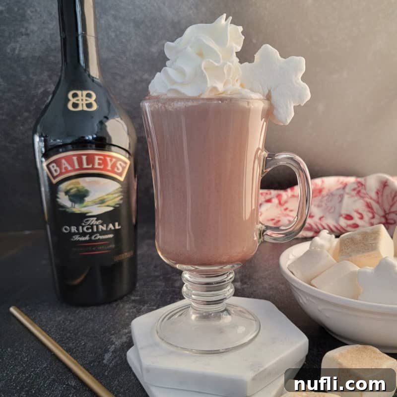 Baileys Hot Chocolate in a glass mug with whipped cream and a snowflake marshmallow.