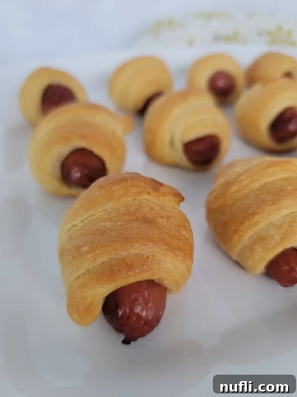 Petite Sausage Parcels 8 crescent dough wrapped around a sausage lined up on a white platter