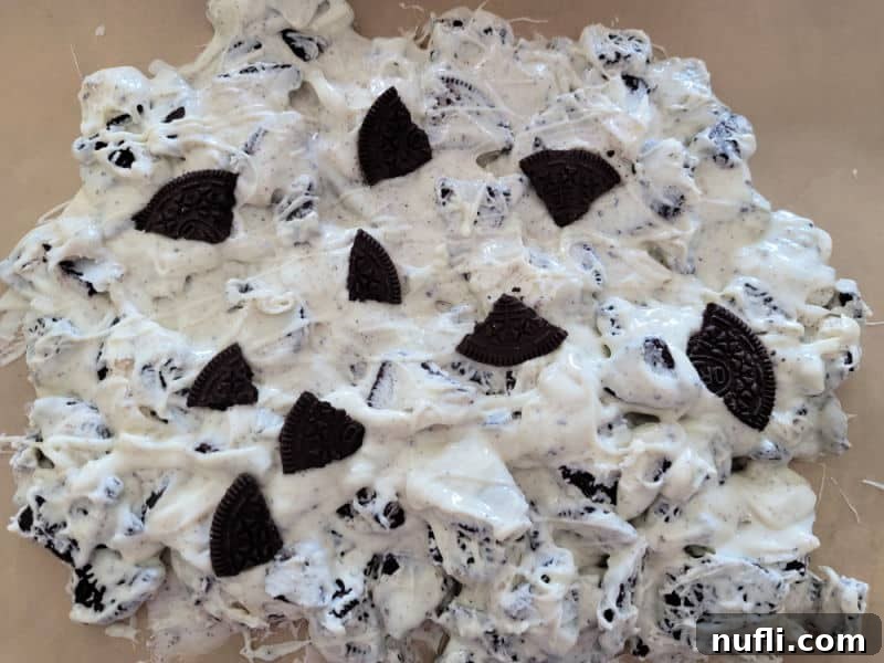 Effortless Two-Ingredient Oreo Bark 7 The mixture of Oreos and melted white chocolate spread evenly on parchment paper on a baking sheet, cooling.